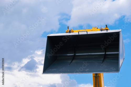 Bucket of loader on a blue sky background. Footprints on the surface. Industrial background. Banner wallpaper. Heavy machinery rental concept. Copy space. 