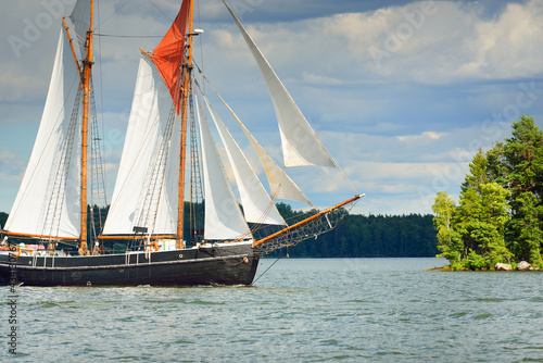 An elegant two-masted gaff schooner (training tall ship) sailing in Mälaren lake, Sweden. Travel, history, traditions, transportation, sailing, sport, cruise, regatta, teamwork. Panoramic view photo