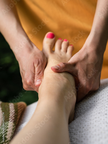 A woman performs feet massage in the forest. Spa in nature. 