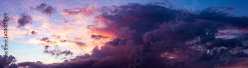 Panoramic view with vibrant blue sky and dramatic sunset contrasting colors of yellow, red and orange touching the cumulus cloud. Weather conditions. Wallpaper poster.