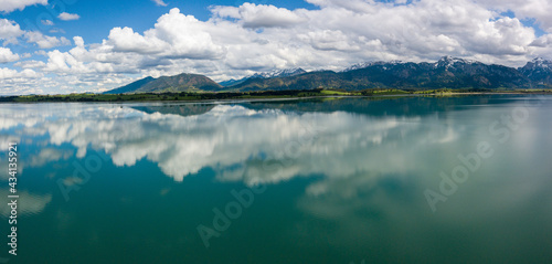 Fototapeta Naklejka Na Ścianę i Meble -  Forggensee Allgäu from above - Aerial view with mirroring clouds on a sunny day at the feet of the alps close to Füssen and Neuschwanstein