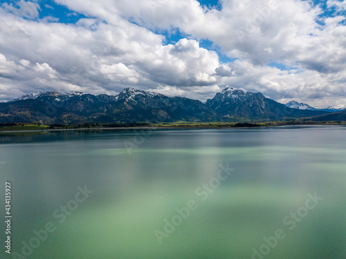 Forggensee Allgäu from above - Aerial view with mirroring clouds on a sunny day at the feet of the alps close to Füssen and Neuschwanstein