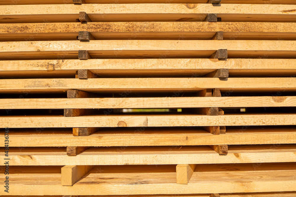 Storage of piles of wooden boards on the sawmill. Boards are stacked in a carpentry shop. Sawing drying and marketing of wood. Pine lumber for furniture production, construction. Lumber Industry.