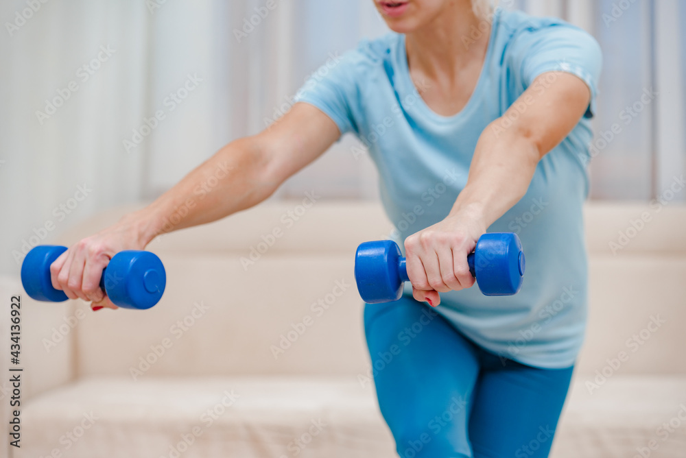 Closeup photo of female athlete doing squatting with dumbbells Closeup photo of female athlete doing squatting with dumbbells