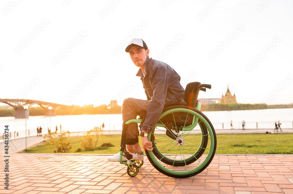 Fototapeta premium Young man in wheelchair and his friend walk outdoors