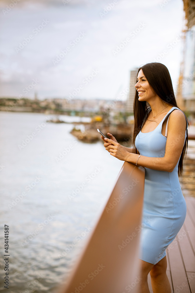 Young woman using a mobile phone while standing on the river promenade