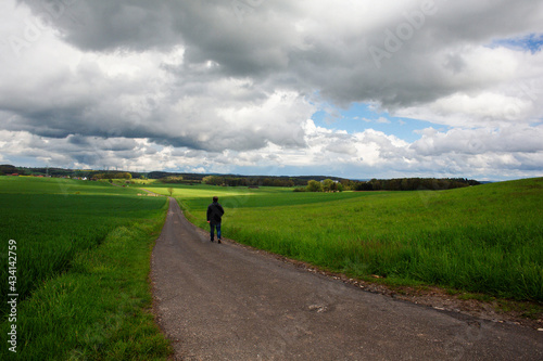Man walking in Bavaria on a country road and getting healthy exercise
