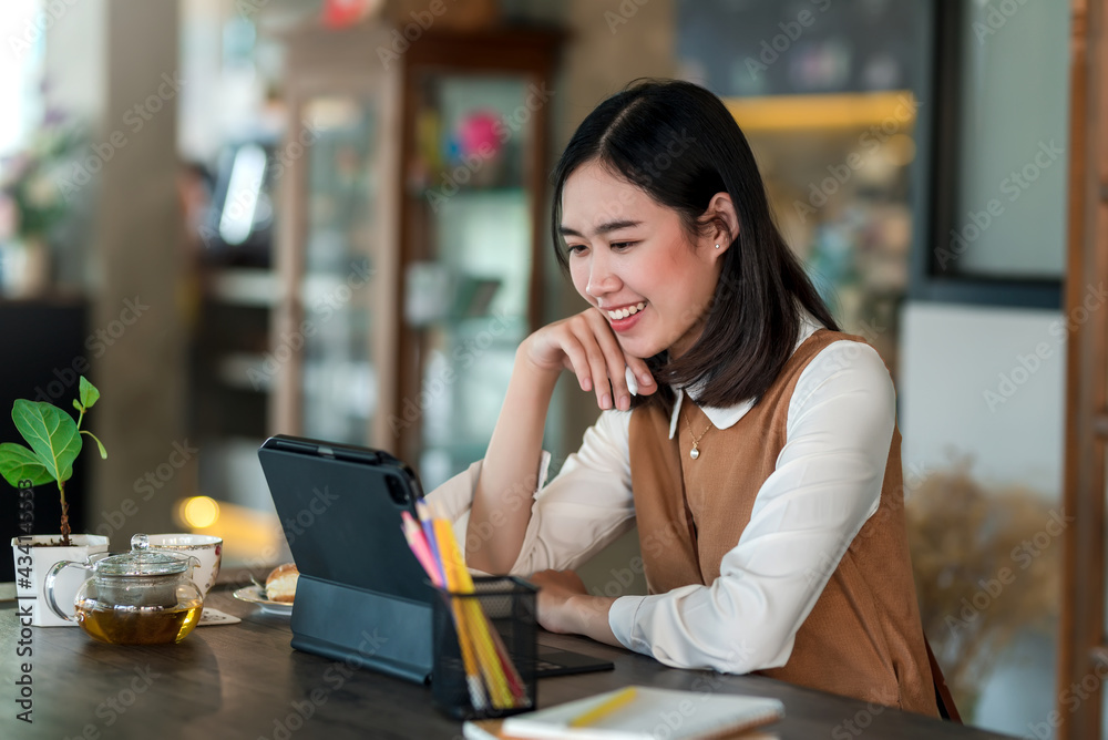 Smiling Asian businesswoman is happy to using a tablet at the café. Smiling Asian businesswoman is happy to using a tablet at the café.