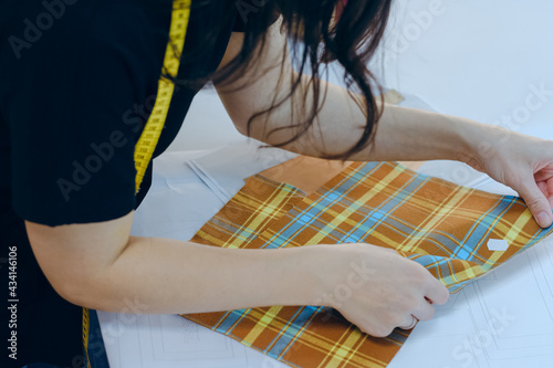 Female tailors hands working with fabric clothes