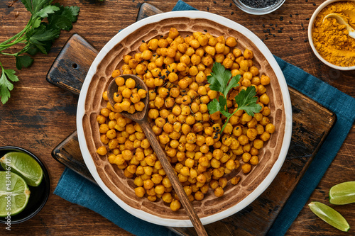 Fried chickpeas with turmeric in ceramic plate on an old wooden table background. Roasted spicy chickpeas or Indian chana or chole, popular snack recipe. Top view.