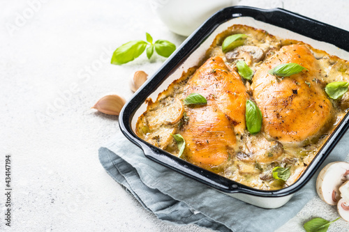 Baked chicken breast with mushrooms in cream sauce on white kitchen table.