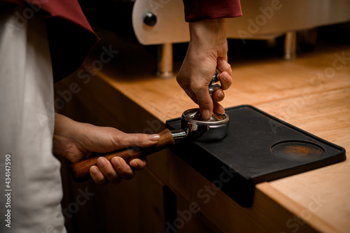 Cuadro en lienzo woman barista presses ground coffee using tamper