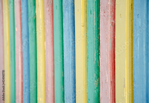 Selective focus multi-colored palisade made of wooden boards. The texture of cracked old paint on wooden planks. The surface of the playground fence. Cozy concept..