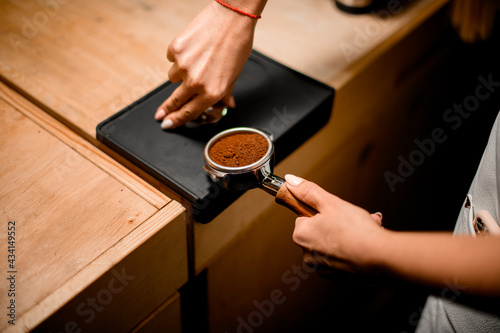 view of baristas hand tamping coffee in portafilter before making fresh drink