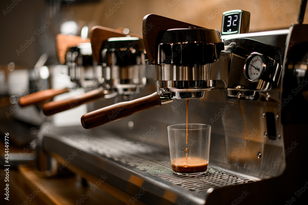 professional coffee machine automatically prepares and pours espresso drink into clear glass