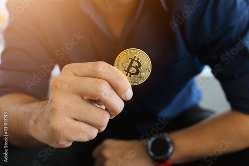 golden bitcoin in a businessman hand in the office with soft focus and backlighting. cryptocurrency concept photo