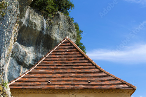 Toiture de maison traditionnelle à forte pente sous une falaise photo