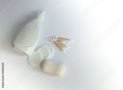 white dispenser bottle with soap bar with cotton pads and ear sticks on white background