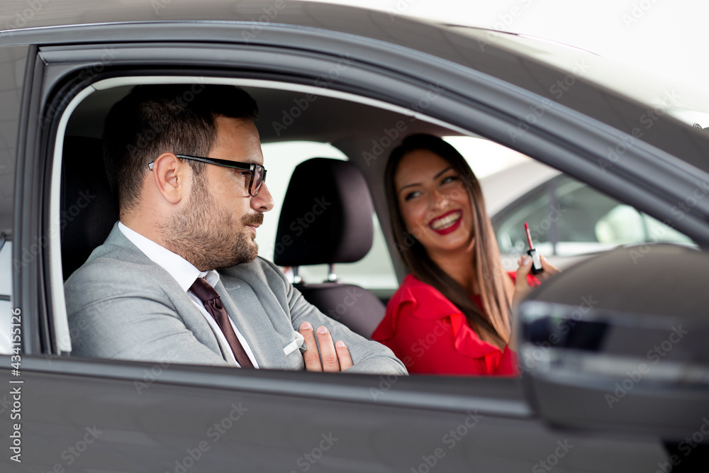 Happy beautiful couple is choosing a new car at dealership