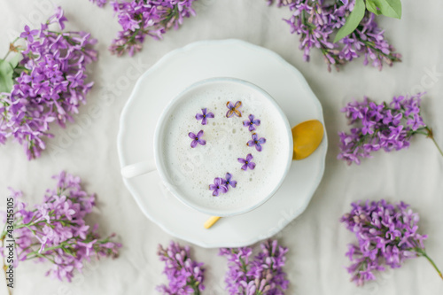 Mug of cappuccino on a beige background. Lilac flowers. Rest at home. Quarantine. © Kristina89