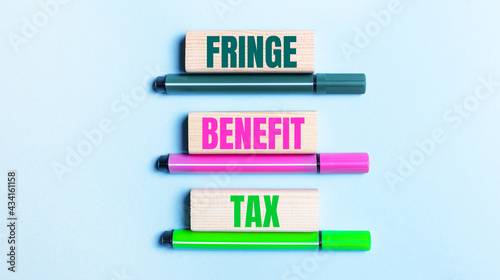 On a light blue background, there are three multi-colored felt-tip pens and wooden blocks with the FRINGE BENEFIT TAX text. © Елена Дигилевич