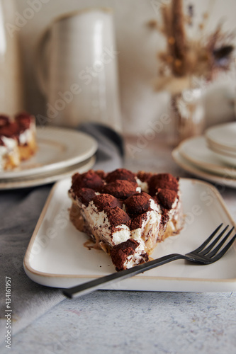 Vertical shot of delicious Bonafi Cream Pie slice with chocolate powder on a white plate with a fork photo