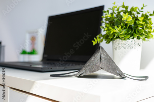 Facemask and laptop on the desk, working from homethe new normal photo