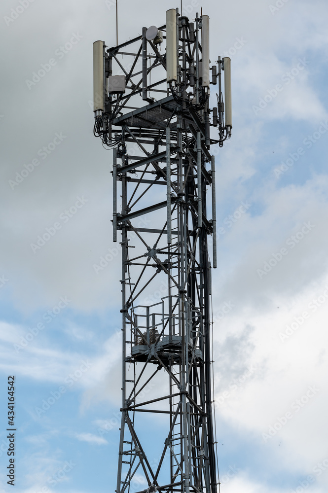 A cell phone tower or mobile phone mast with the remnants of a large birds nest on a landing platform approximately half way up A cell phone tower or mobile phone mast with the remnants of a large birds nest on a landing platform approximately half way up