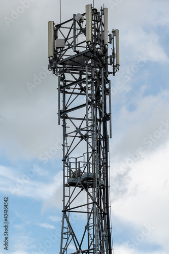 A cell phone tower or mobile phone mast with the remnants of a large birds nest on a landing platform approximately half way up