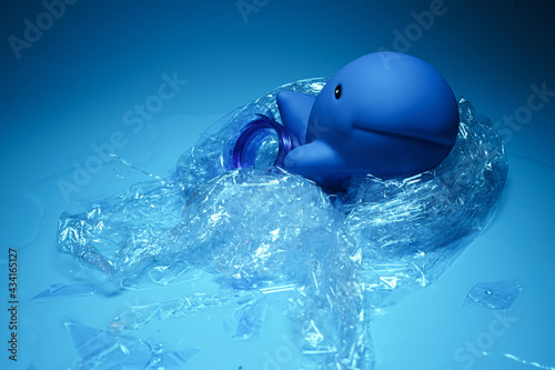Arrangement of blue toy dolphin wrapped in plastic debris representing ocean environmental problems