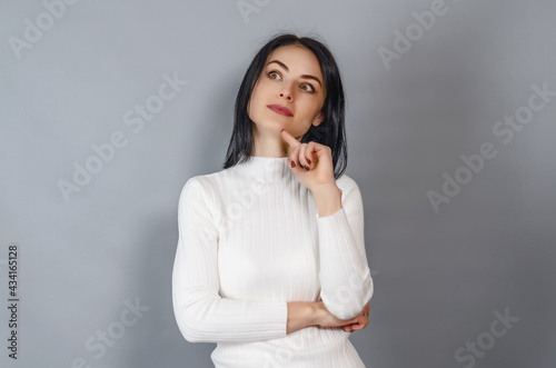 Pretty woman in a white sweater looks at the camera. Portrait of a successful businesswoman