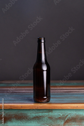 Dark glass bottle of alcoholic drink on painted square shaped wooden table at home photo