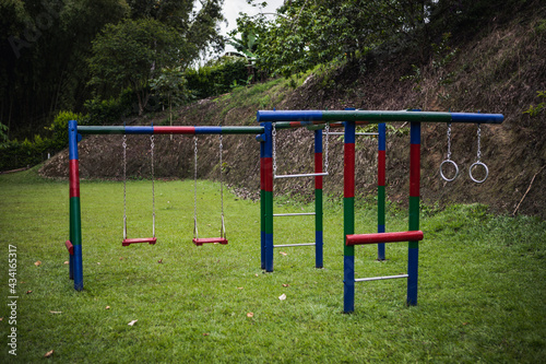 Multicolored playground playset with swings and climbing equipment located on grassy meadow in green park in Armenia Colombia