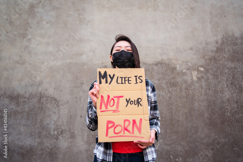 Ethnic female in protective mask standing with My Life Is Not Your Porn carton poster during protect against sexual harassment and assault photo