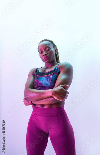 Self assured African American sportswoman in activewear with folded arms and biceps looking at camera photo