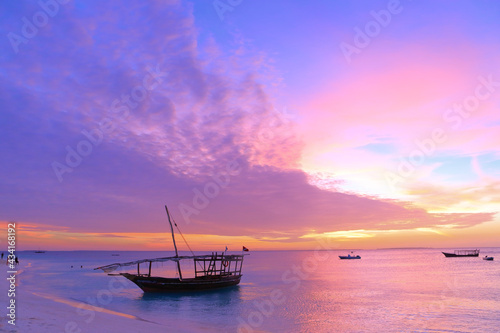 Sunset on Zanzibar. Authentic african wooden boat on the picturesque ocean shore