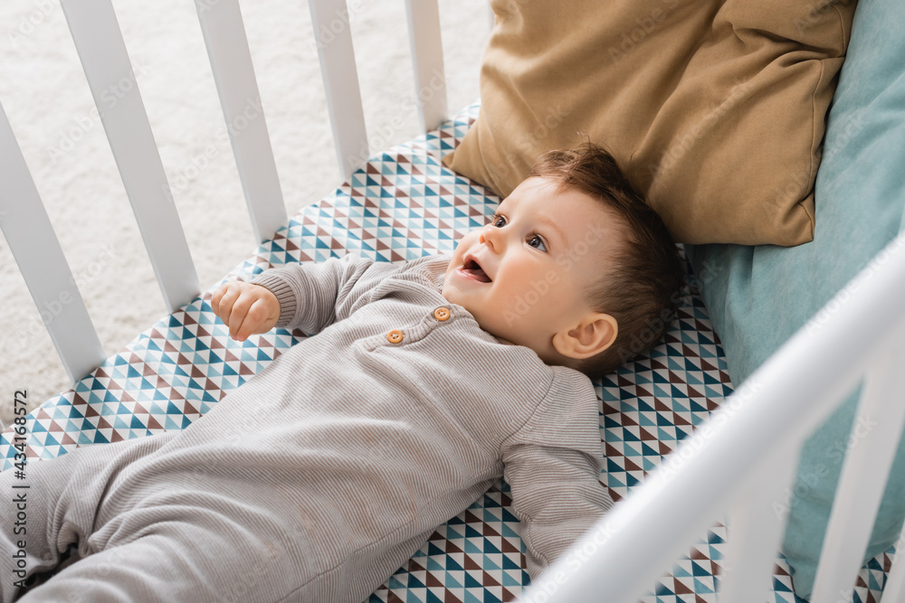 high angle view of infant boy lying in baby crib - obrazy, fototapety, plakaty 