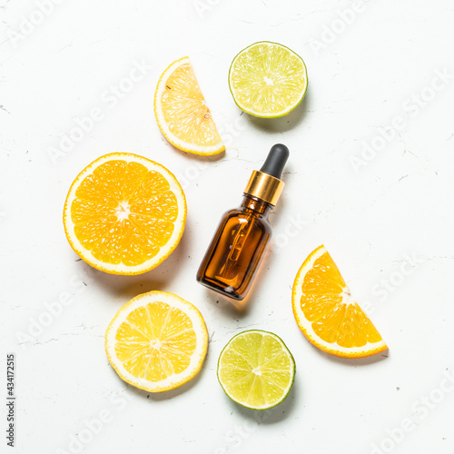 Vitamin C. Anti aging cosmetic. Fresh citrus fruits with serum bottle. Top view at white background.