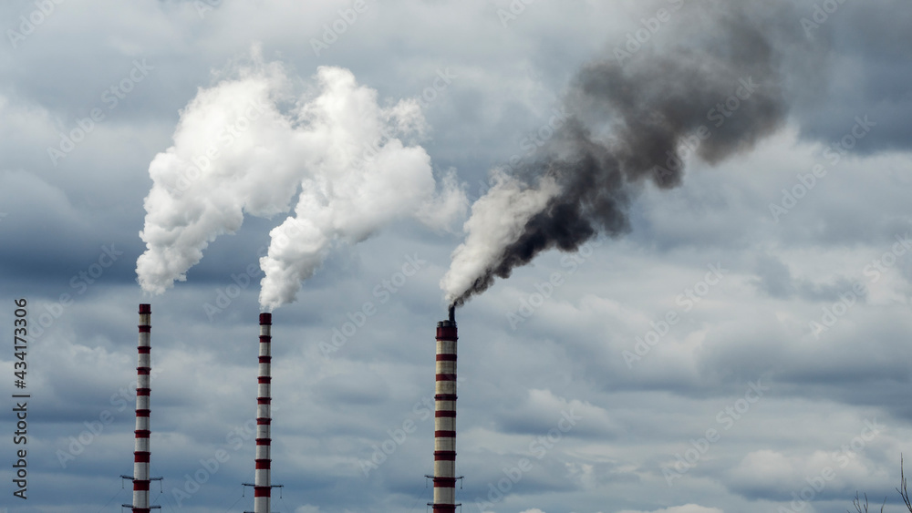 Industrial smoke from chimney on dramatic sky background. View of high chimney pipes with grey smoke from coal power plant. Production of electricity with fossil fuel. Wind blowing pollution. Industrial smoke from chimney on dramatic sky background. View of high chimney pipes with grey smoke from coal power plant. Production of electricity with fossil fuel. Wind blowing pollution.