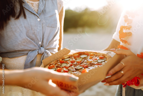 Hands taking slices of pizza close view. Friends eating pizza at the beach. Fast food concept. Beach holiday and summer vacation concept.
