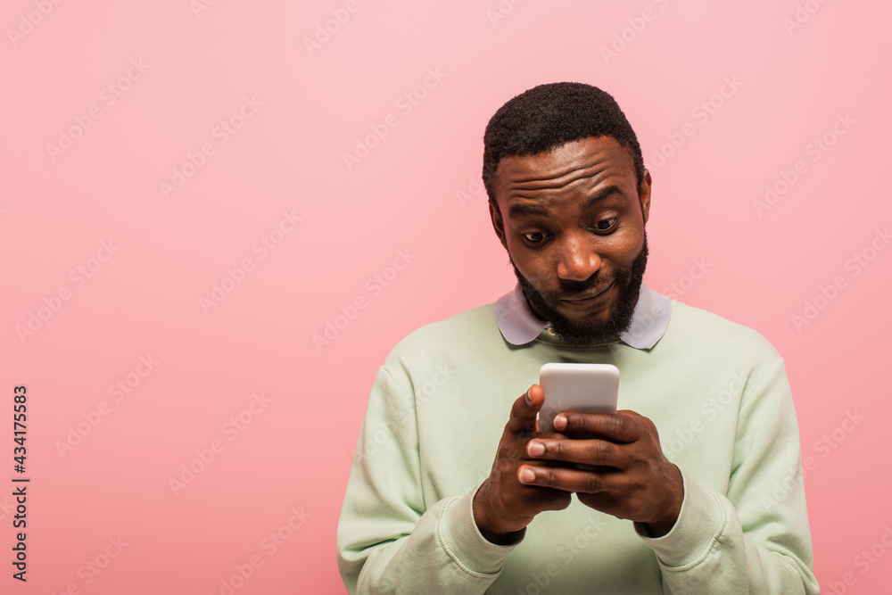 African american man texting on smartphone isolated on pink African american man texting on smartphone isolated on pink