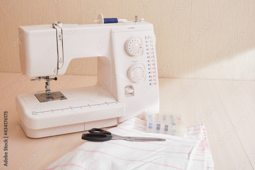 sewing machine, fabric, scissors and spools of thread on the table