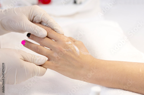 Hand massage with nourishing and moisturizing cream is done by a specialist in gloves after the manicure procedure. The concept of professional hand care with a copy of the space.