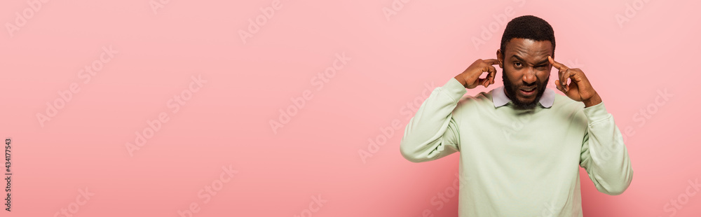 Confused african american man pointing at head on pink background, banner Confused african american man pointing at head on pink background, banner