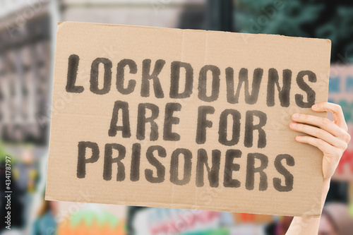 The phrase " Lockdowns are for prisoners " on a banner in hand with blurred background. Restrictions. Forbidden. Prohibition. Policy. Rules. Stressed. Depressive. Issue. Healthcare system © AndriiKoval