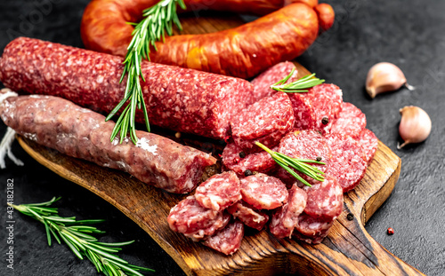 Assortment of smoked sausages and sausages with mold on a stone background 