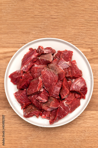 Cooking pilaf in a cauldron, a recipe for real pilaf. Ingredients for cooking pilaf on a wooden background. Raw meat on a wooden cutting board, cut into pieces
