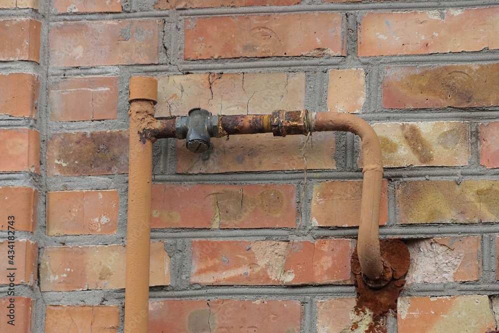 iron gas pipe on brown brick wall outside