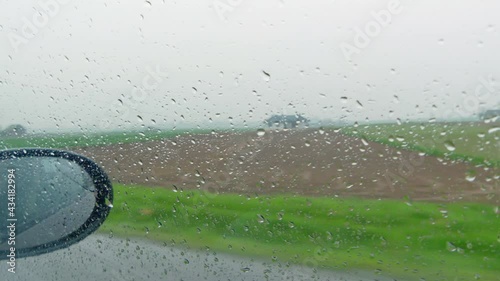 view of raindrops on the side window of the car. blurry rainy landscape behind the glass