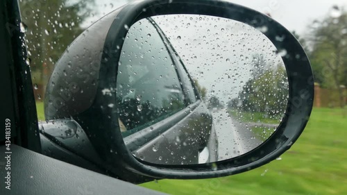 view of a rain-fallen car mirror, while driving through heavy rainfall